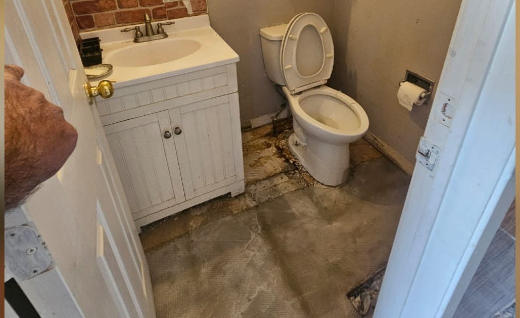 Before: dated powder room with exposed brick and water-damaged floor